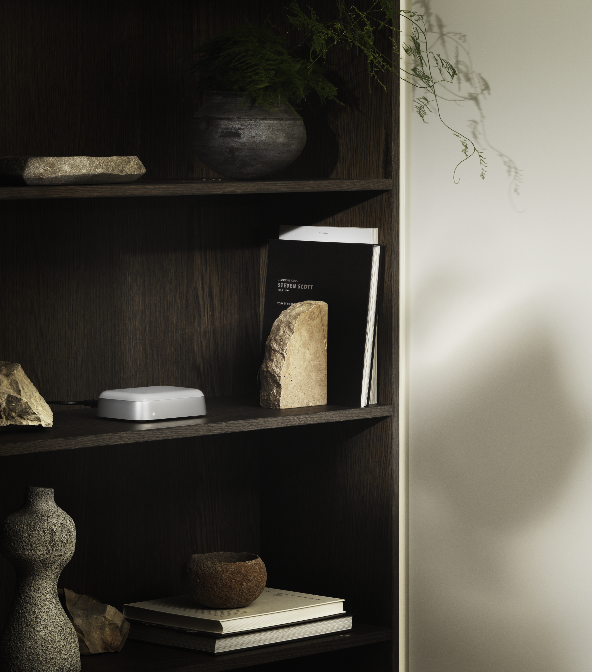 Beoconnect Core in aluminum, displayed on a shelf in a modern home